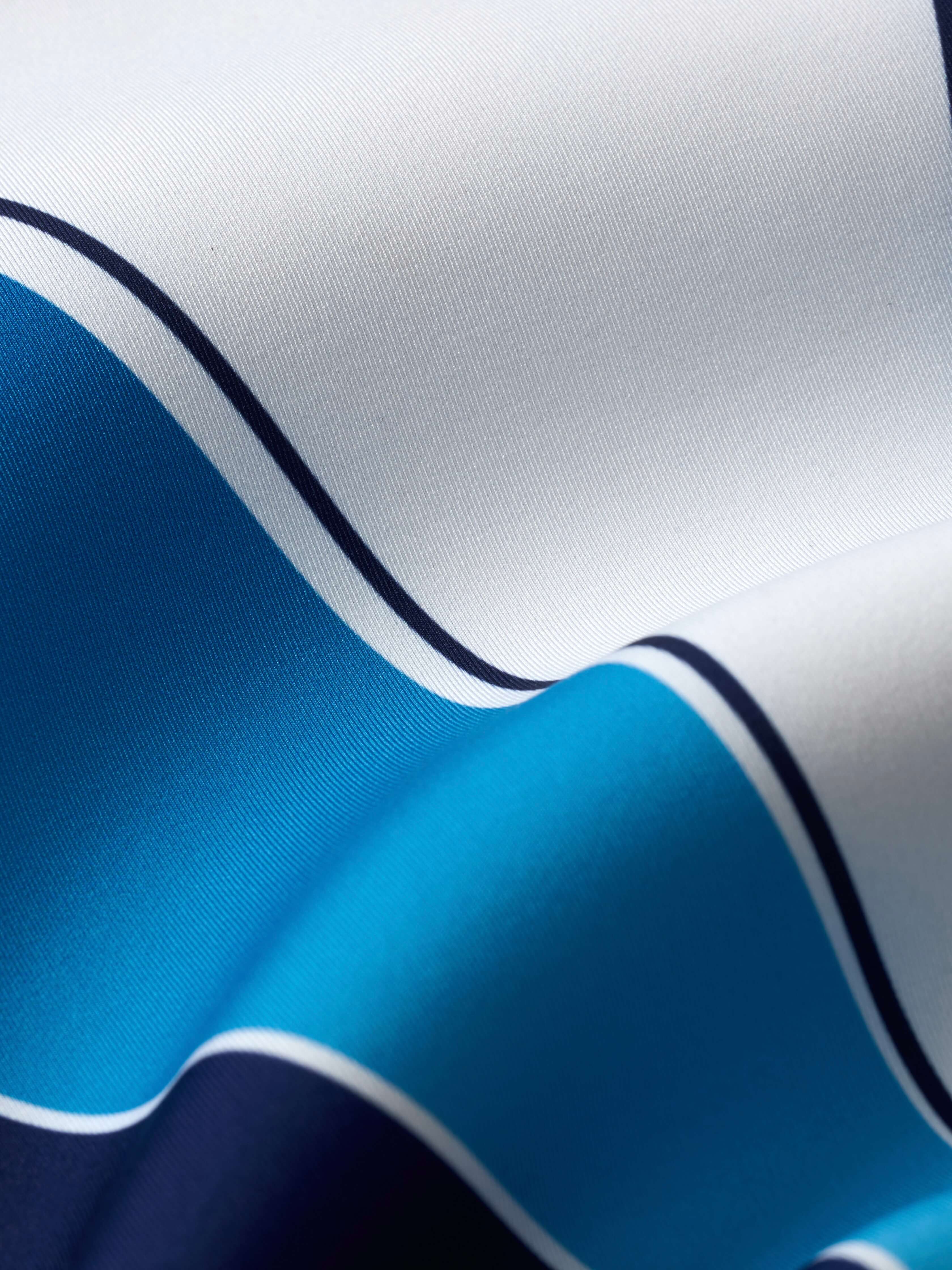 Yanita springsuit neoprene fabric close-up showing smooth white, turquoise, and navy surface finish with curved seam lines