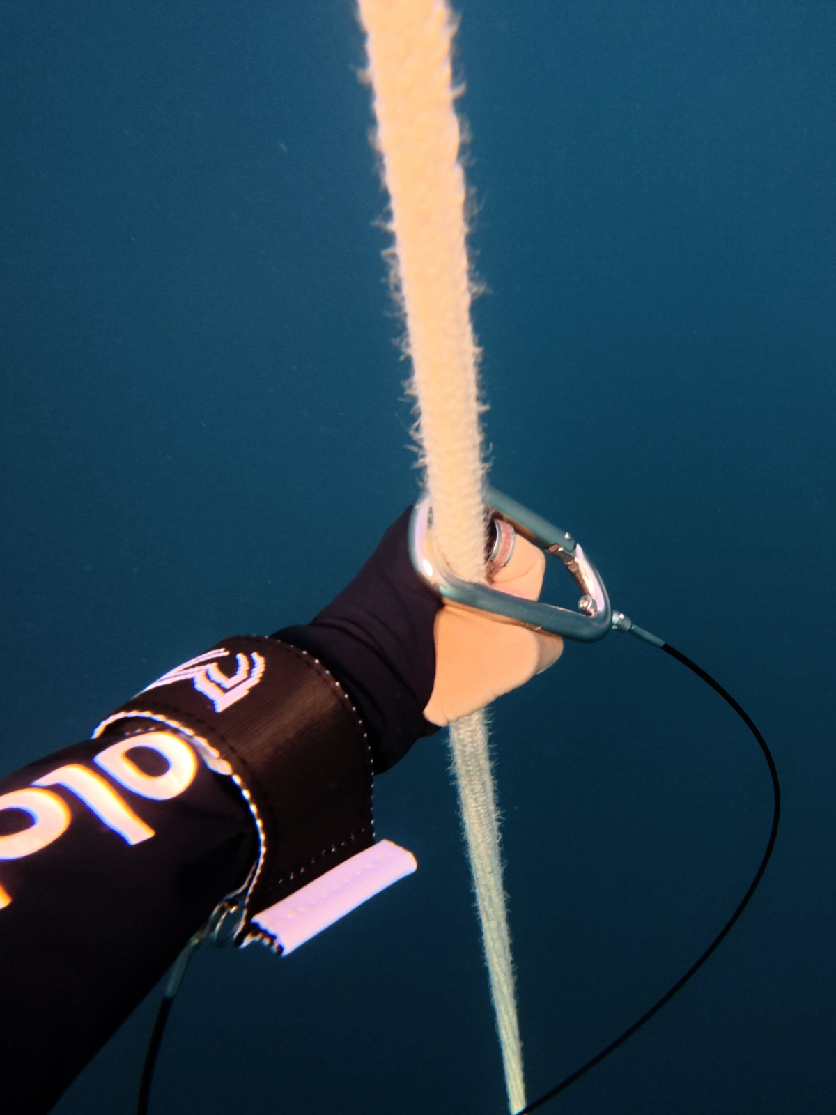 Freediver underwater wearing lanyard cuff clipped to rope