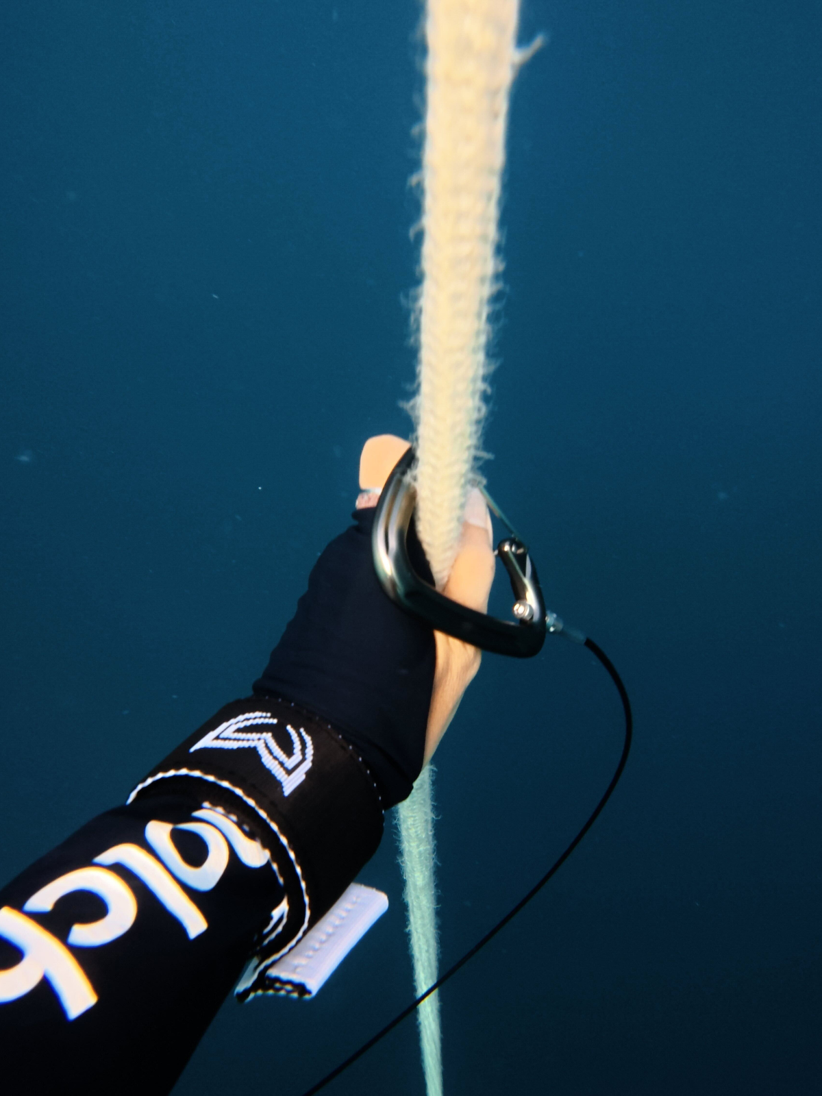 Freediver wearing lanyard wrist cuff holding rope underwater