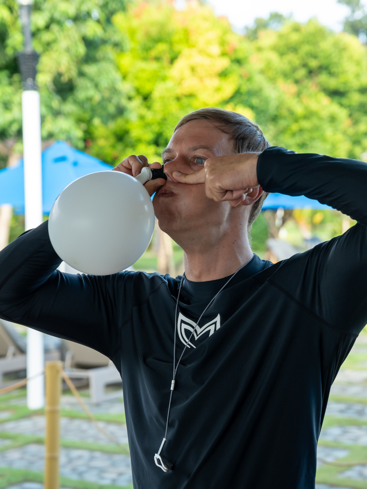 Freediver using Molchanovs EQ Trainer 2 to inflate a balloon for dry mouthfill equalization practice outdoors