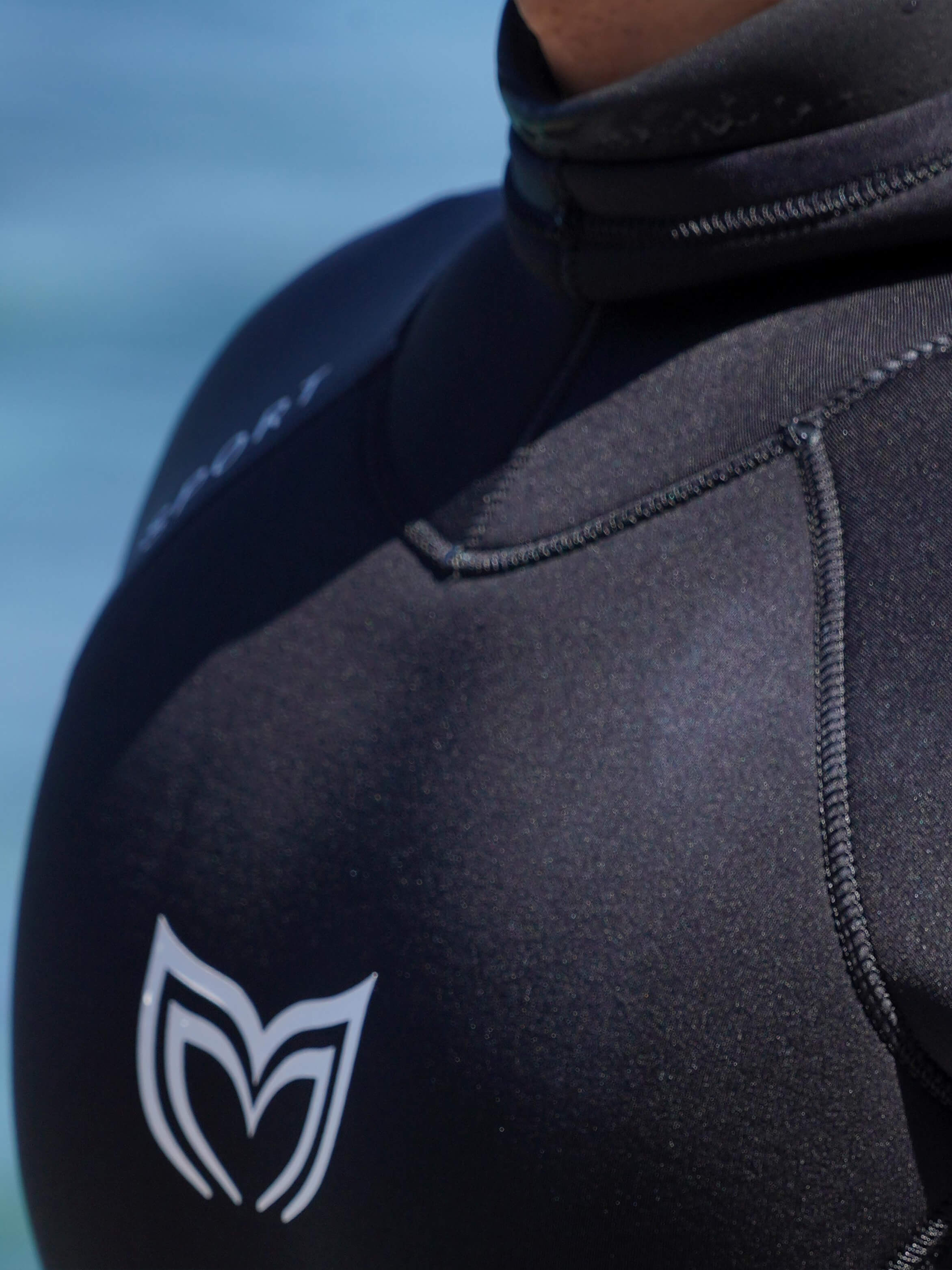 Close-up of the Molchanovs logo and double-lined neoprene stitching on the shoulder of a mens black freediving wetsuit