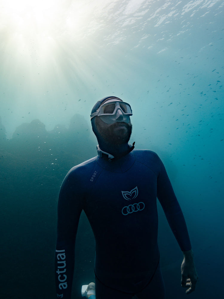 Male freediver wearing the Molchanovs CORE dive mask and Sport wetsuit, photographed underwater in open ocean