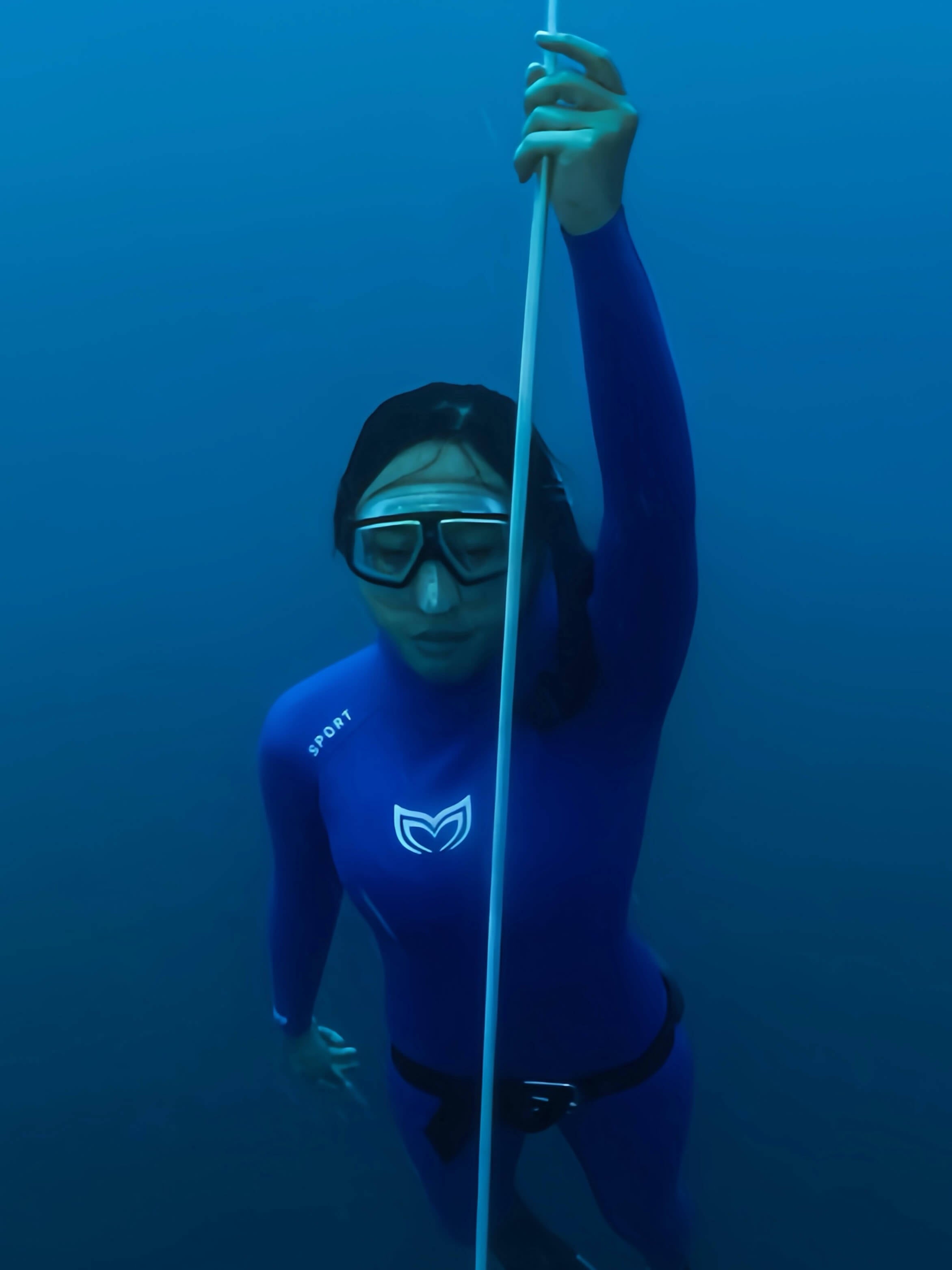 Female freediver ascending a rope underwater wearing the Molchanovs SPORT blue open cell wetsuit