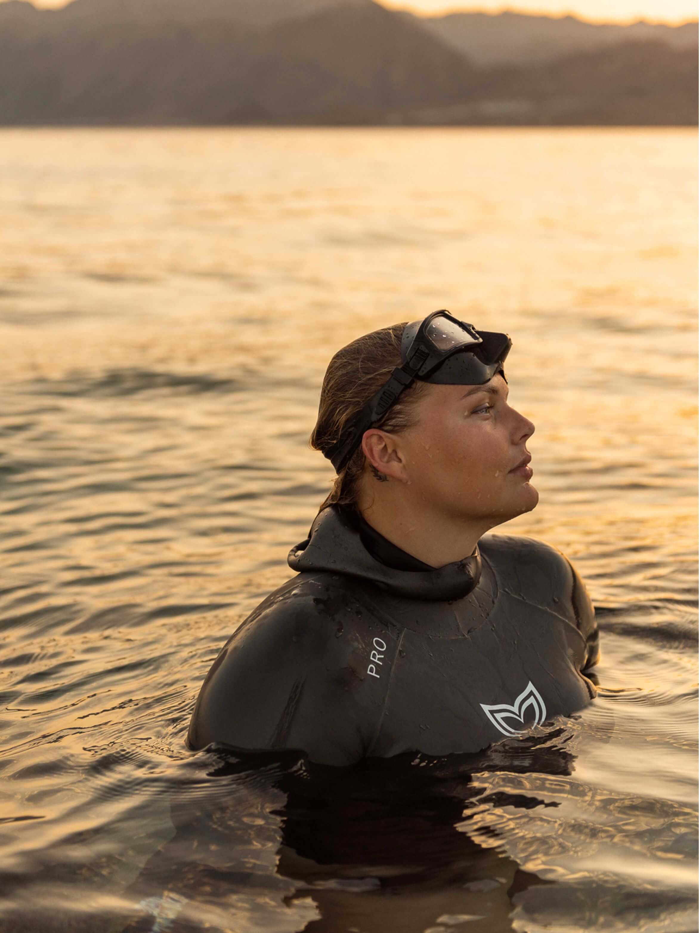 Woman wearing the Molchanovs PRO unlined wetsuit at the surface in open water at sunset