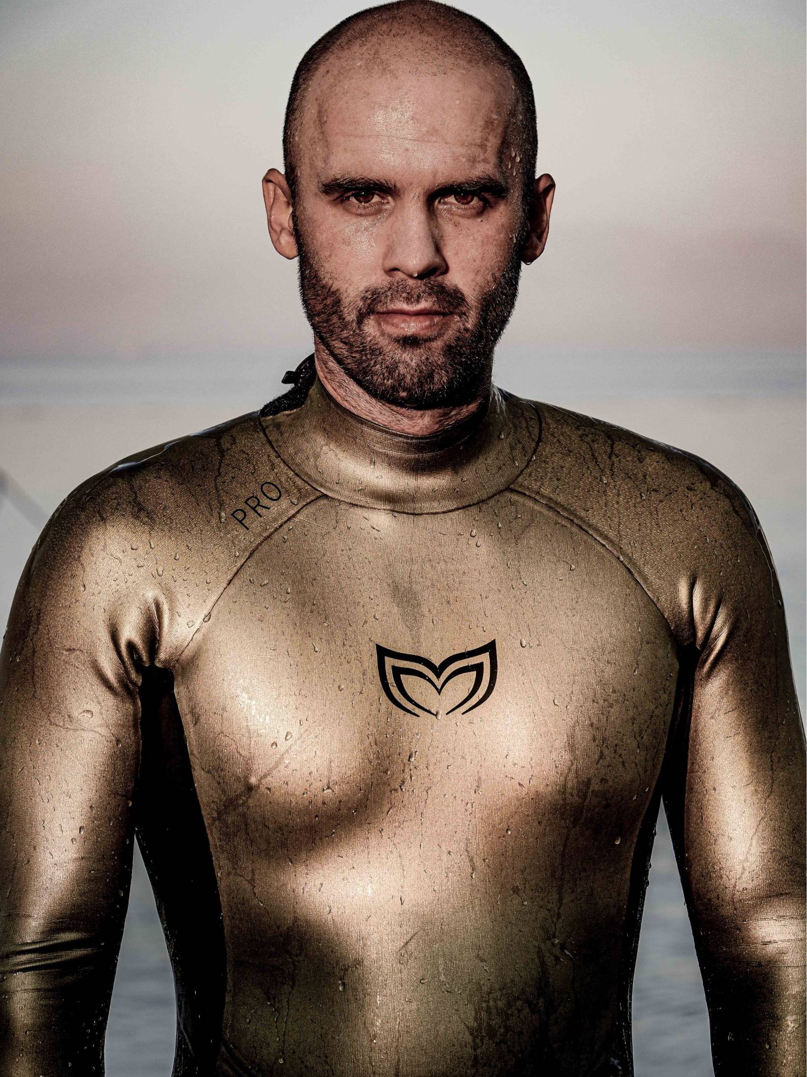 Close-up portrait of a male freediver wearing the Molchanovs PRO wetsuit in gold after a dive