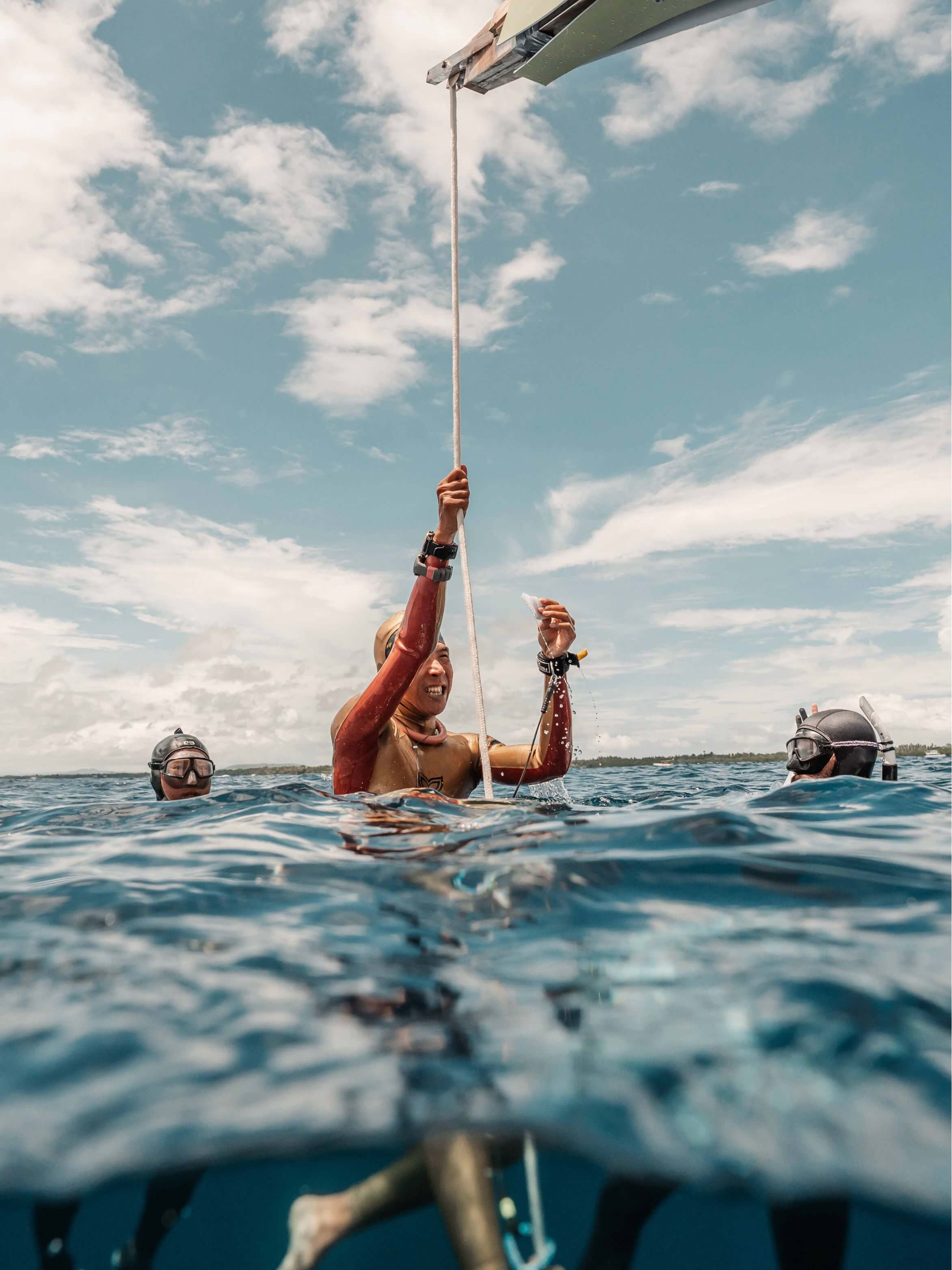 Freediver in Molchanovs PRO wetsuit surfacing at a dive line in open ocean during a competition