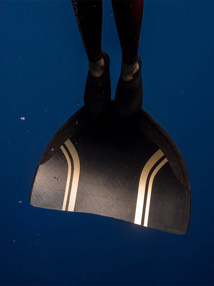 PRO Monofin 4X Carbon blade photographed underwater from below, carbon weave and gold accent stripes visible