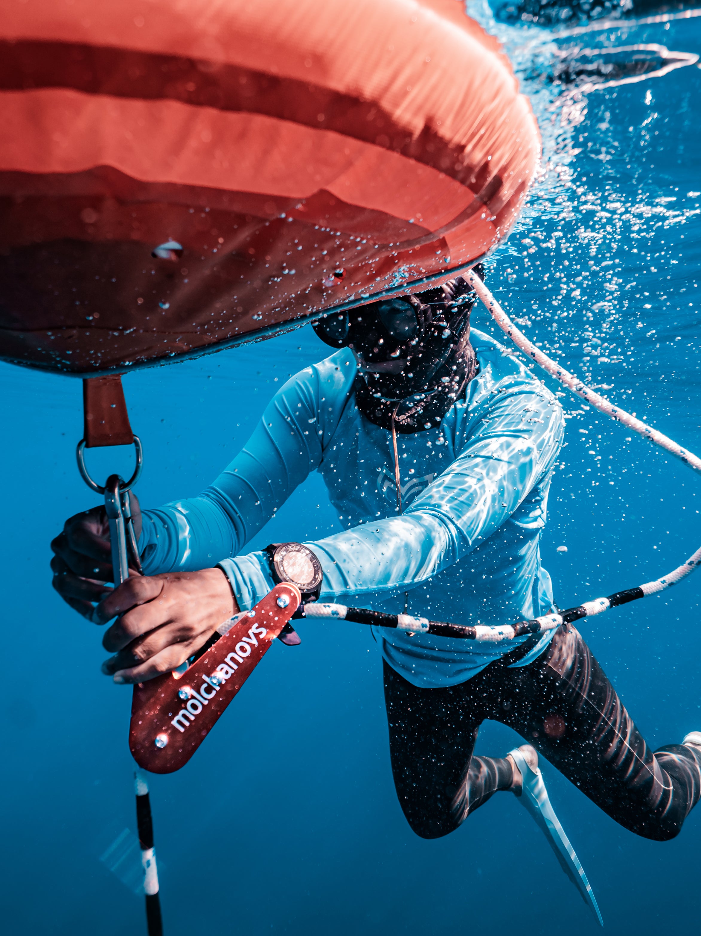Safety freediver adjusting the Molchanovs A6061 rope pulley on the dive line below a red buoy