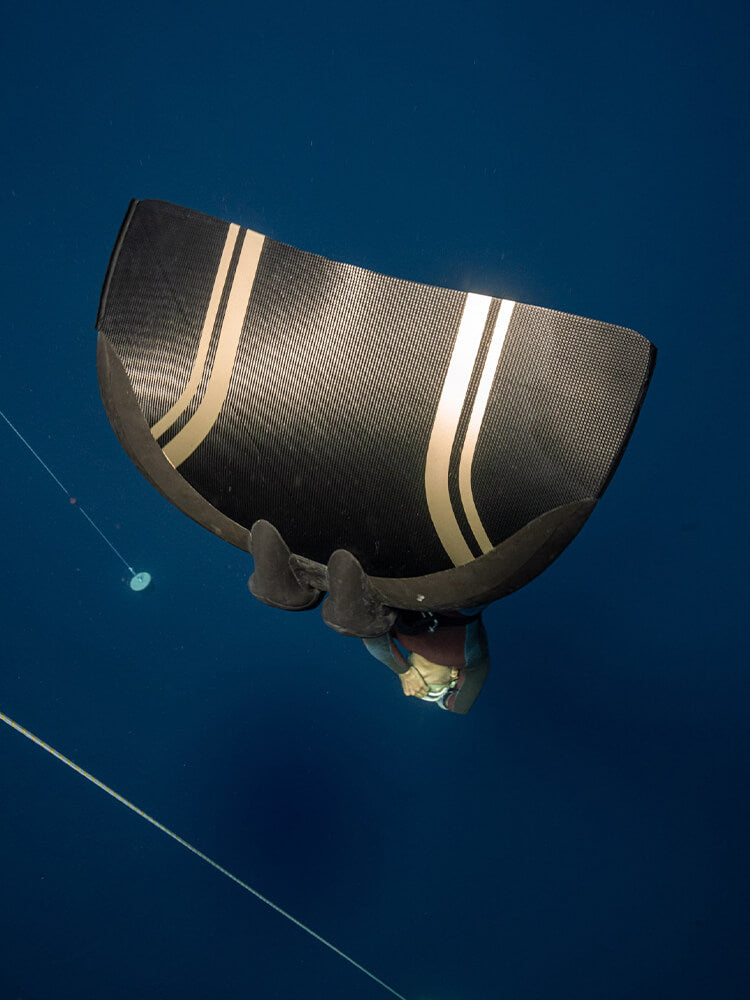 PRO Monofin 4X Carbon blade from below during a freedive, showing carbon fiber weave and dual accent stripes