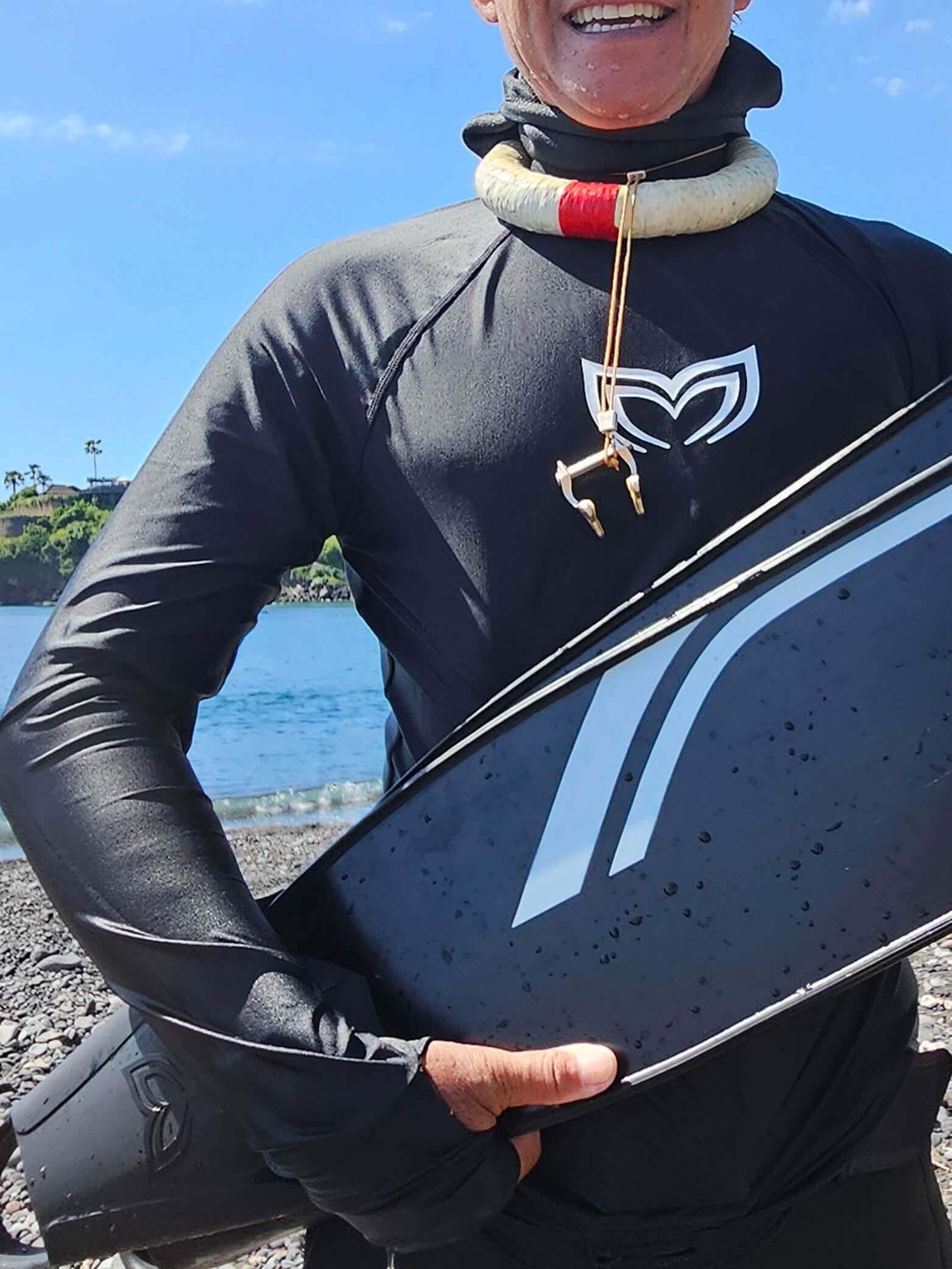 Close-up of the Molchanovs wing logo on the chest of a black UPF 50+ rash guard worn at a beach dive session