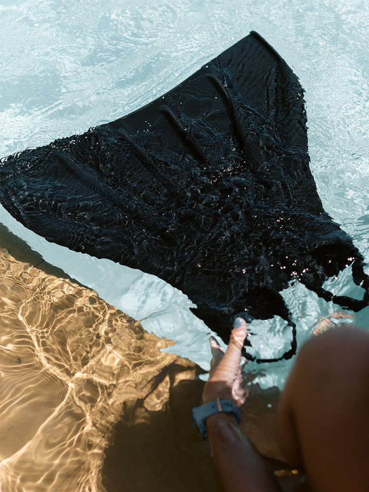 Molchanovs CORE Silicone Monofin blade floating at the water surface, held by a freediver poolside