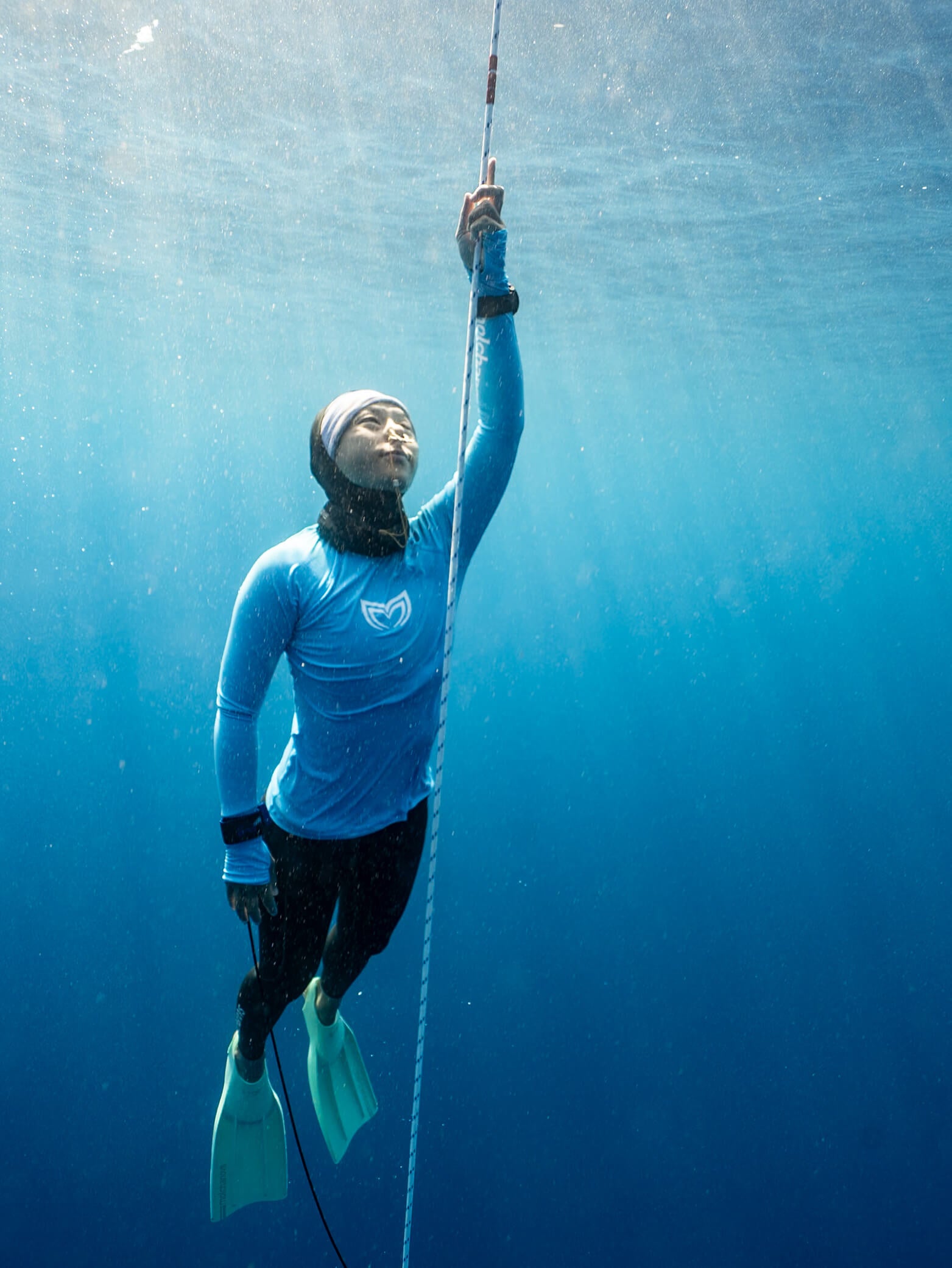 Freediver ascending a vertical dive line underwater wearing a Molchanovs lanyard on the wrist