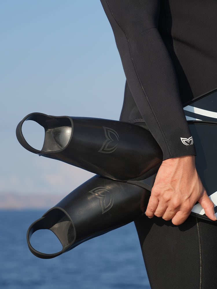 Close-up of two Molchanovs PRO Bifins 3 Fiberglass rubber foot pockets held by a freediver, showing embossed logo detail