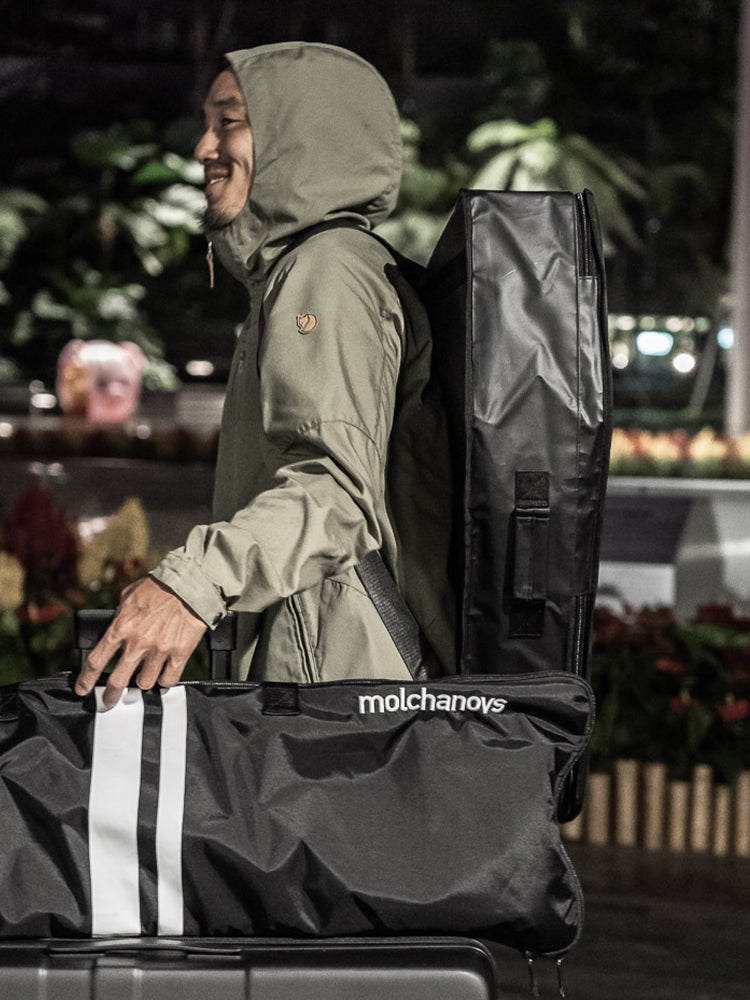 Freediver carrying the Molchanovs Bifins Bag 3 as a backpack at an airport, black version with white stripes