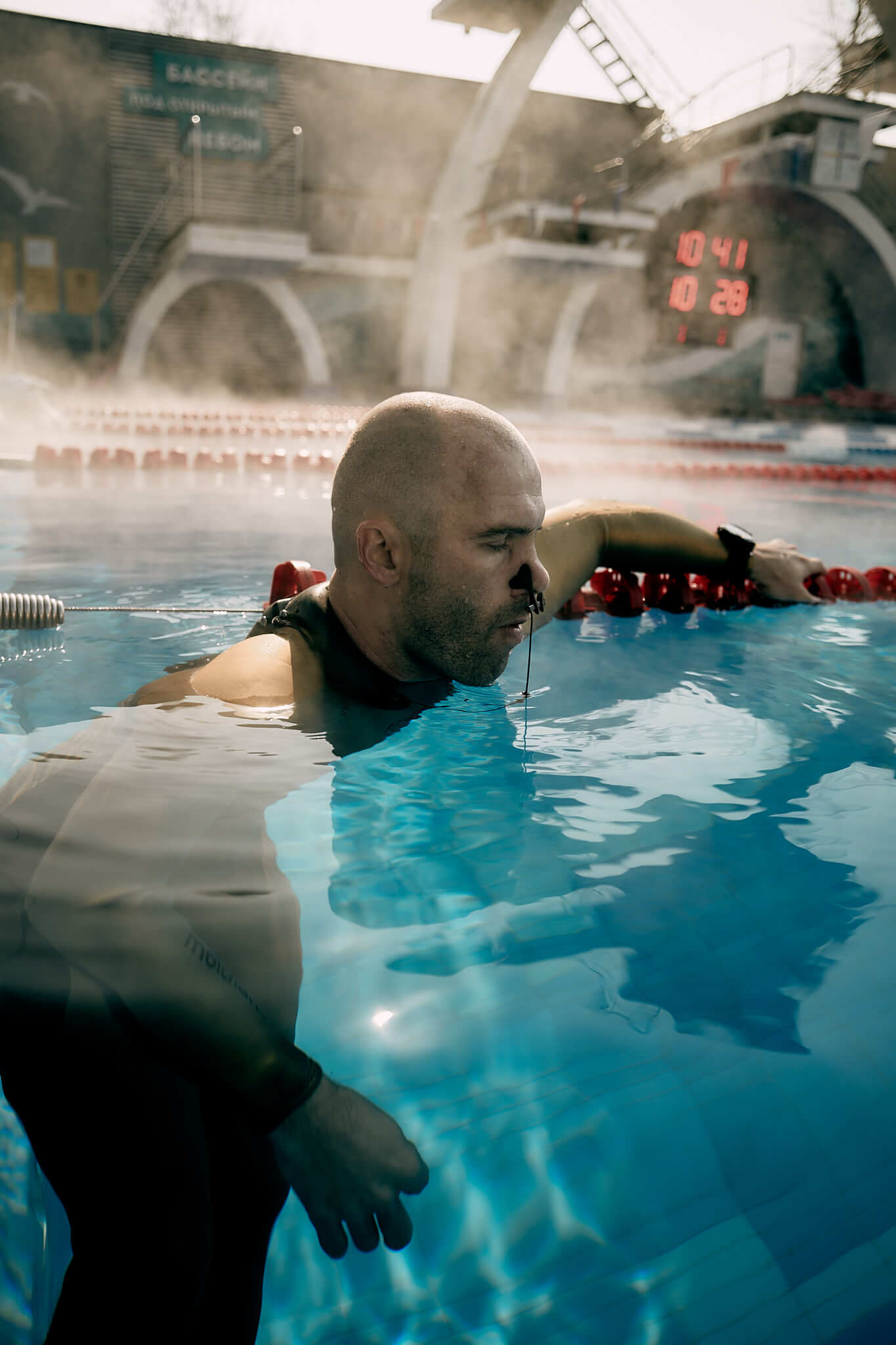 Freediver in a Molchanovs wetsuit resting at the pool edge, preparing for a breath-hold training session