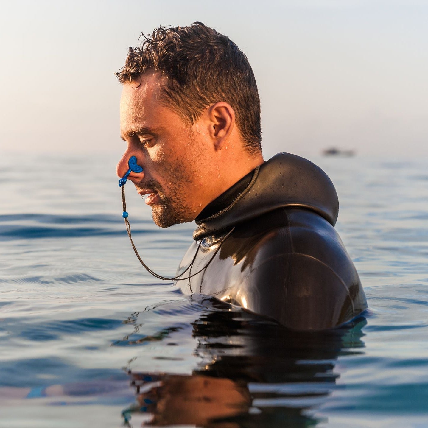 Freediver at the surface wearing a wetsuit and nose clip, preparing for a breath-hold dive