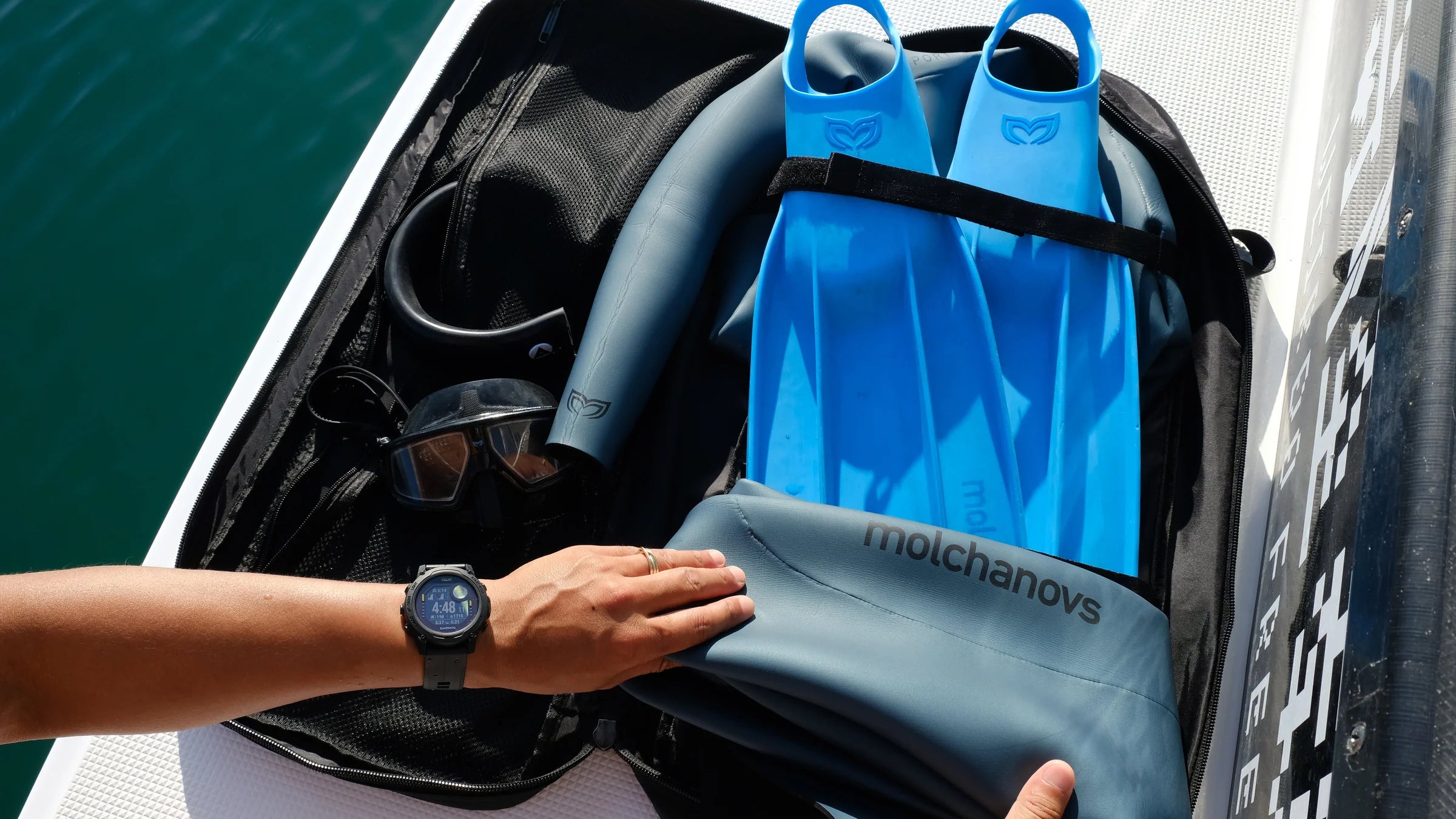 Molchanovs freediving fins bag open on a boat deck with blue bifins and a dive mask inside